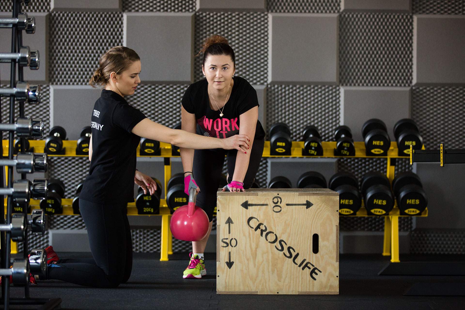 Kobieta wraz z trenerką osobistą ćwiczy z użyciem kettleball mięśnie pleców.
