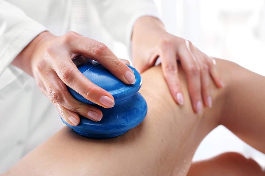 Masażystka wykonująca masaż bańką chińską uda, masaż ogumowanymi bańkami do masażu, RehaFit